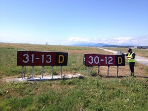 A Vancouver Airport Authority employee replacing the 30-12 crosswind runway sign with a new 13-31 sign to reflect the realigment of the runway with the shifting magnetic heading.